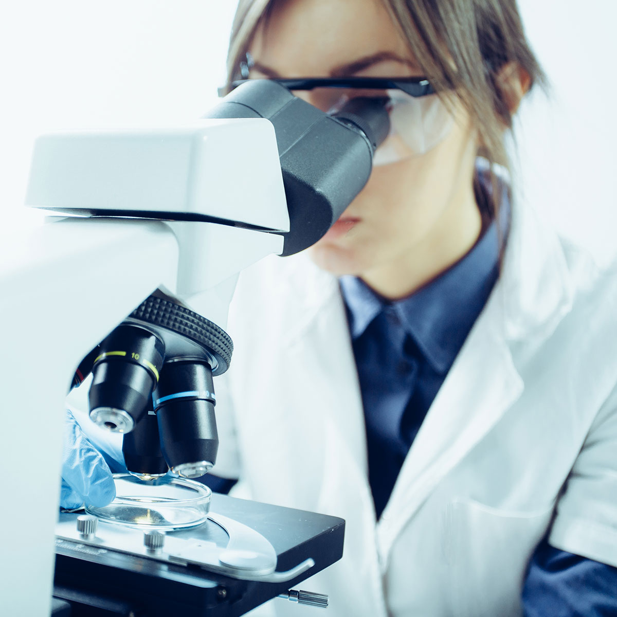 Jeune scientifique regardant à travers un microscope dans un laboratoire